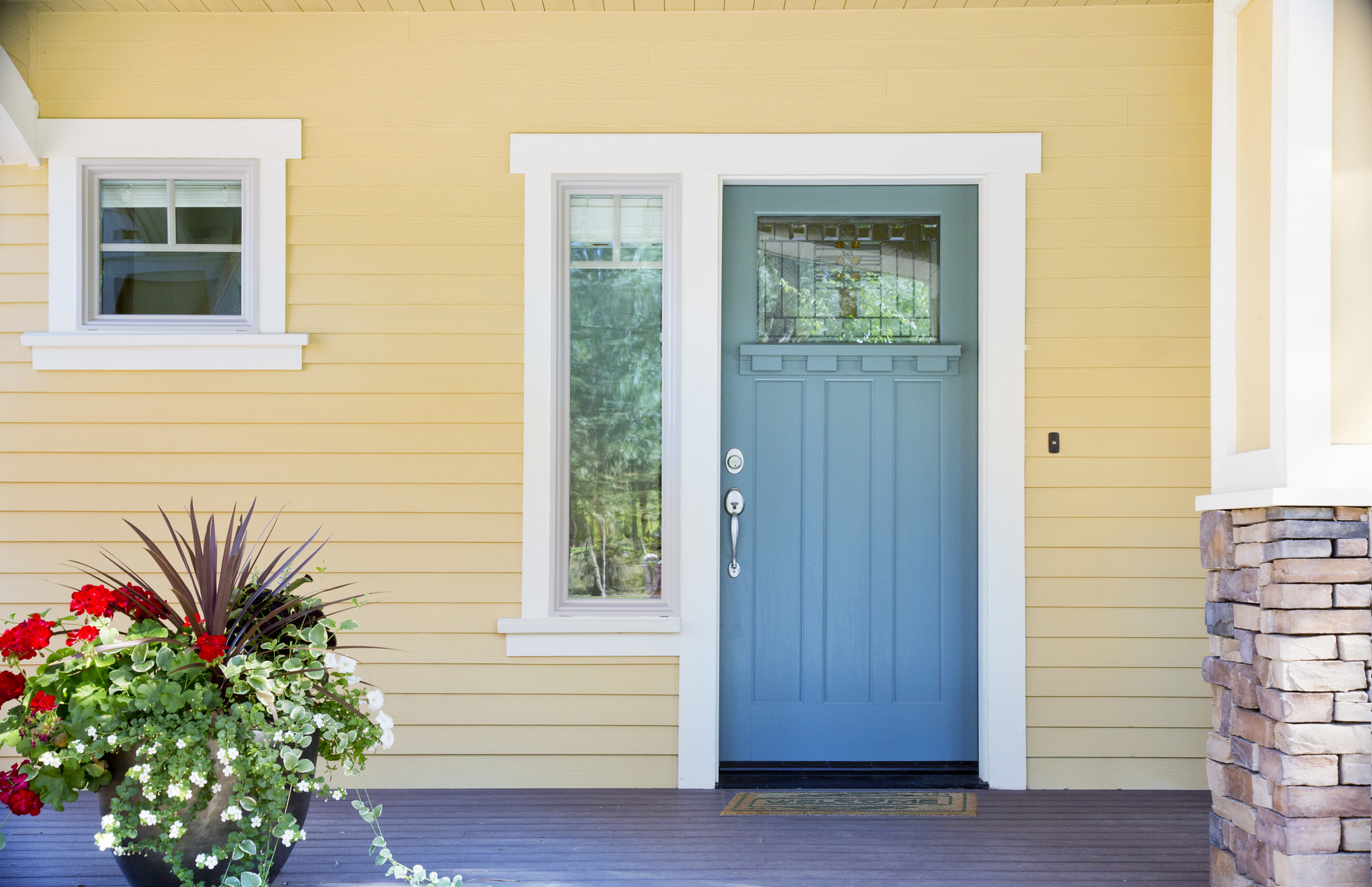 Fachada de casa com paredes em amarelo. As janelas e portas estão da cor azul e contornos brancos.