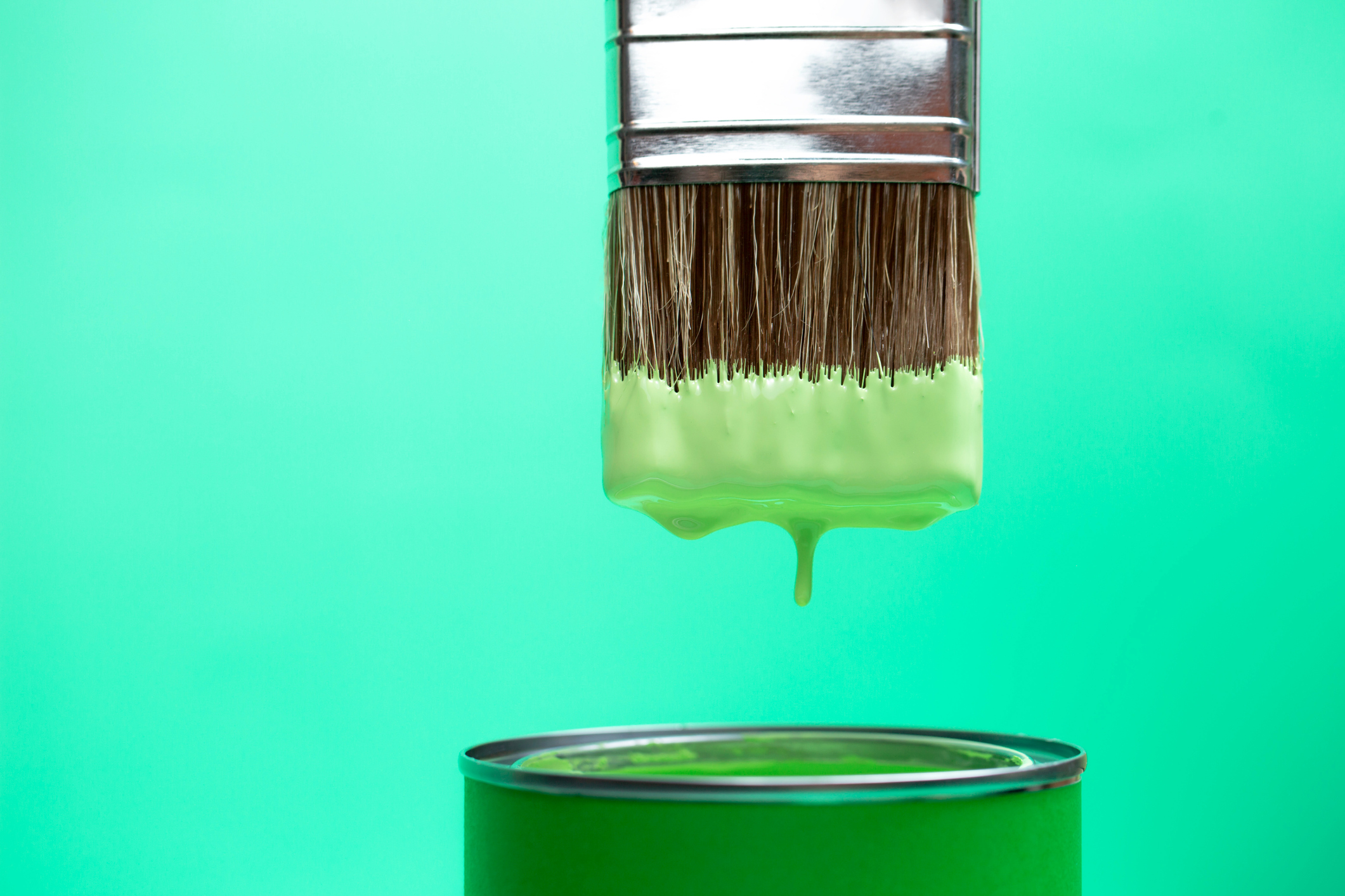 Pincel sendo molhado em uma lata com tinta verde.