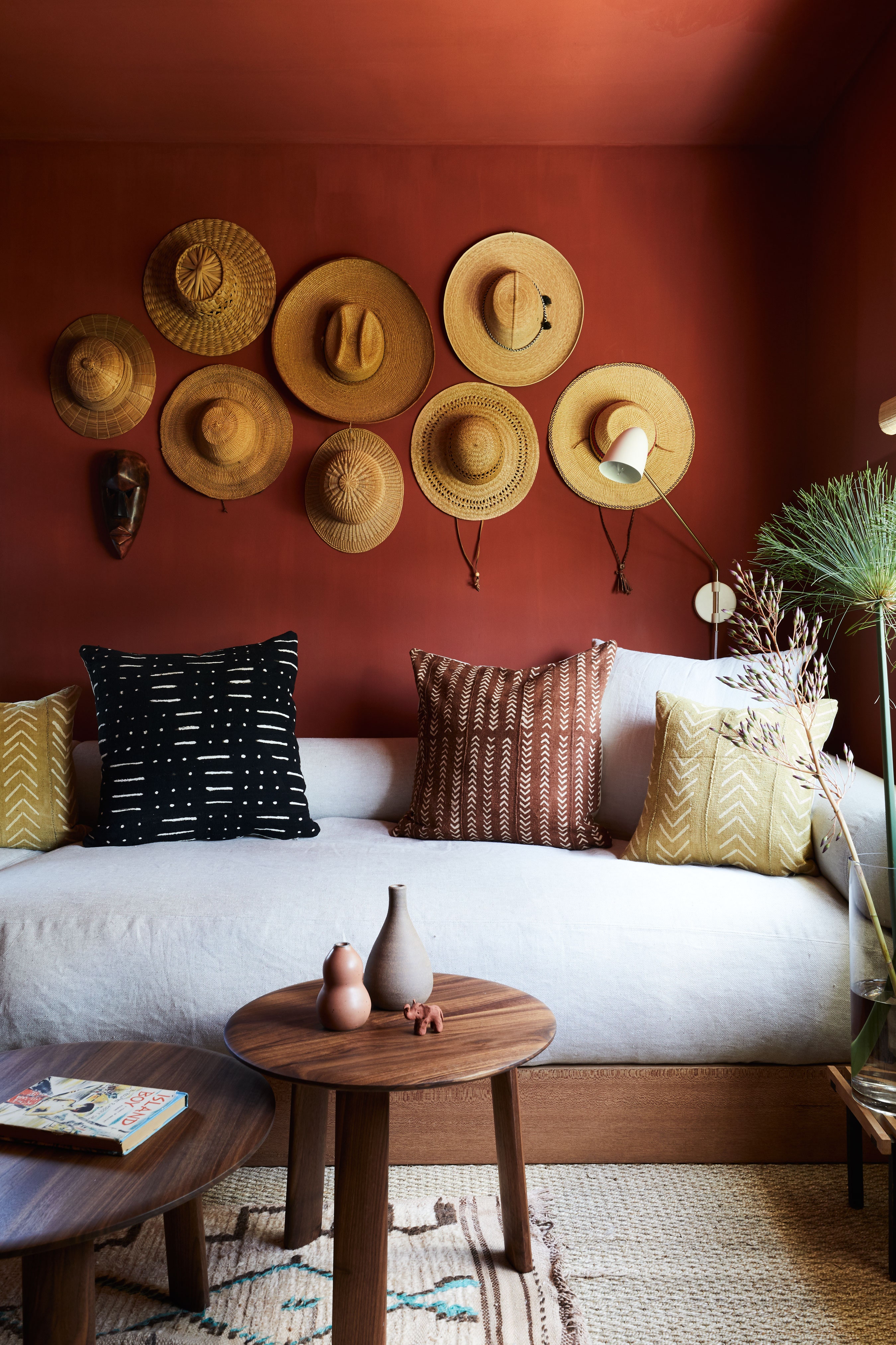 Sala pintada com vermelho e decorada com materiais naturais, como algodão, palha e madeira.